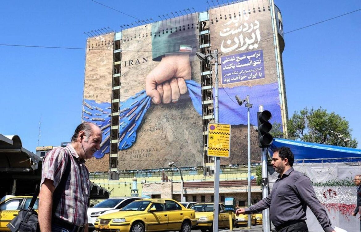 Big billboard showing a fist pulling a blue cloth away from a map, with 'IRAN' text; street scene with yellow taxis and pedestrians.